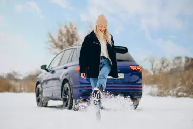 Woman in winter cloths standing by her car
