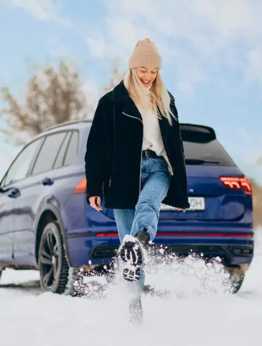Woman in winter cloths standing by her car