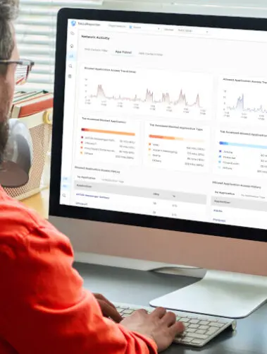 Mężczyzna przy ekranie komputera, na którym wyświetla się usługa Zyxel SecuReporter