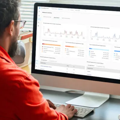 Zyxel Networks prezentuje bezhasłowe logowanie i zabezpieczenia oparte na AI 27 Mężczyzna przy ekranie komputera, na którym wyświetla się usługa Zyxel SecuReporter