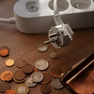 Na stoliku monety i portfel, obok listwa - przedłużacz