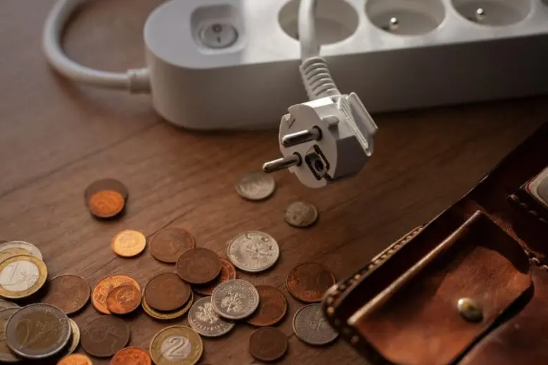Na stoliku monety i portfel, obok listwa - przedłużacz