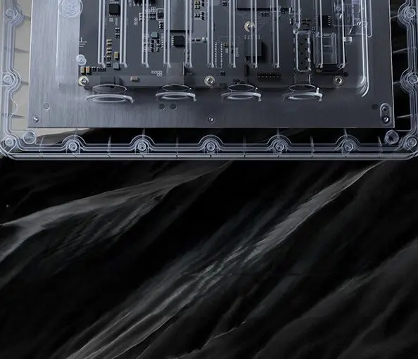 Przezroczysta obudowa punktu dostępowego Zyxel WBE665S, ukazująca wewnętrzne układy elektroniczne i płytę główną, umieszczona nad pofałdowaną, czarną strukturą przypominającą skały lub ciemną materię.