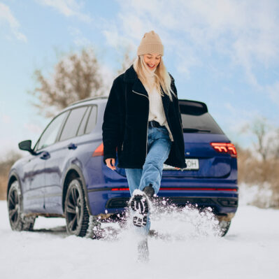 Woman in winter cloths standing by her car