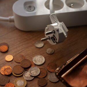Na stoliku monety i portfel, obok listwa - przedłużacz