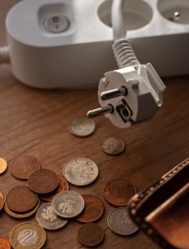 Wysokie zużycie energii elektrycznej w sezonie grzewczym. Jak sobie z nim poradzić? 32 Na stoliku monety i portfel, obok listwa - przedłużacz